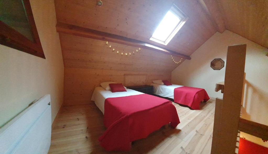 a attic room with two beds and a window at Auverg'Nature Chambre Auvergnate massage ayurvédique in Espinasse