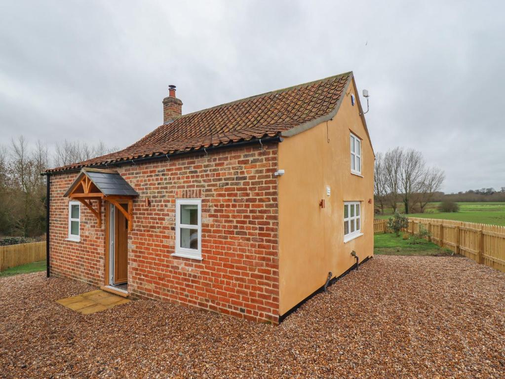 a small brick house in a yard with a fence at Shepherd's Cottage in Alford