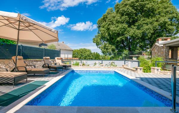 a swimming pool with chairs and an umbrella next to a house at Apartman Genova Imotski in Donji Vinjani