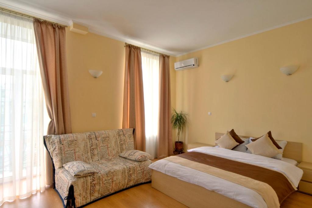 Heart Kyiv Apart-Hotel في كييف: غرفة نوم بسرير واريكة ونوافذ