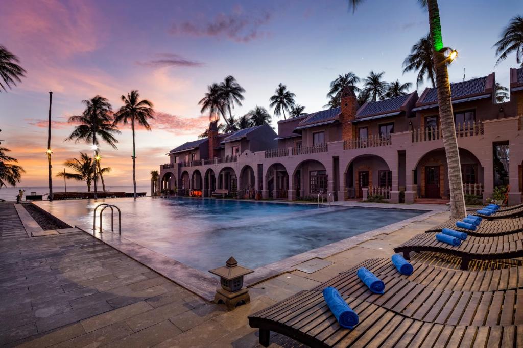 um resort com piscina e palmeiras em Le VIVA Resort Mui Ne em Mui Ne