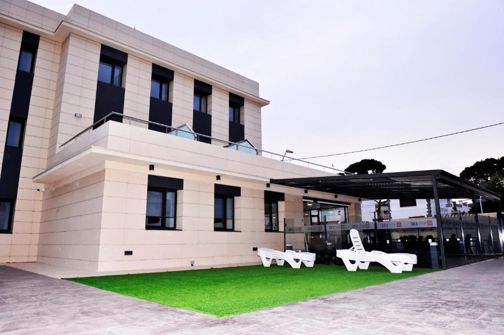 two white benches sitting in front of a building at 6 Bis HOTEL in Castelldefels