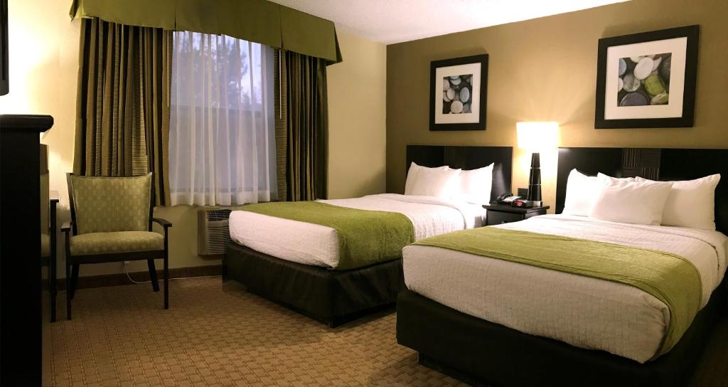 een hotelkamer met 2 bedden en een stoel bij NavajoLand Hotel in Tuba City