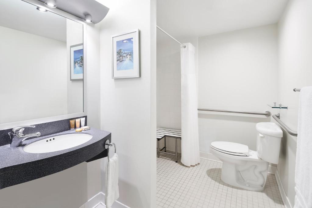 ein Badezimmer mit Toilette, Waschbecken und Spiegel in der Unterkunft Club Quarters Hotel Embarcadero, San Francisco in San Francisco