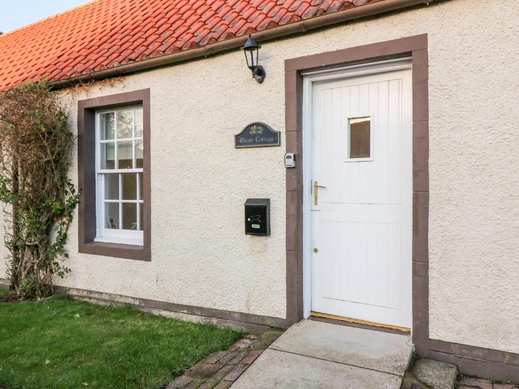 a house with a white door and a sign on it at Rhum Cottage in Cupar
