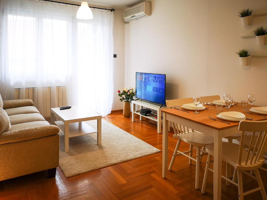 uma sala de estar com uma mesa, um sofá e uma televisão em FilinHome Dusana 3-bedroom Suite em Novi Sad