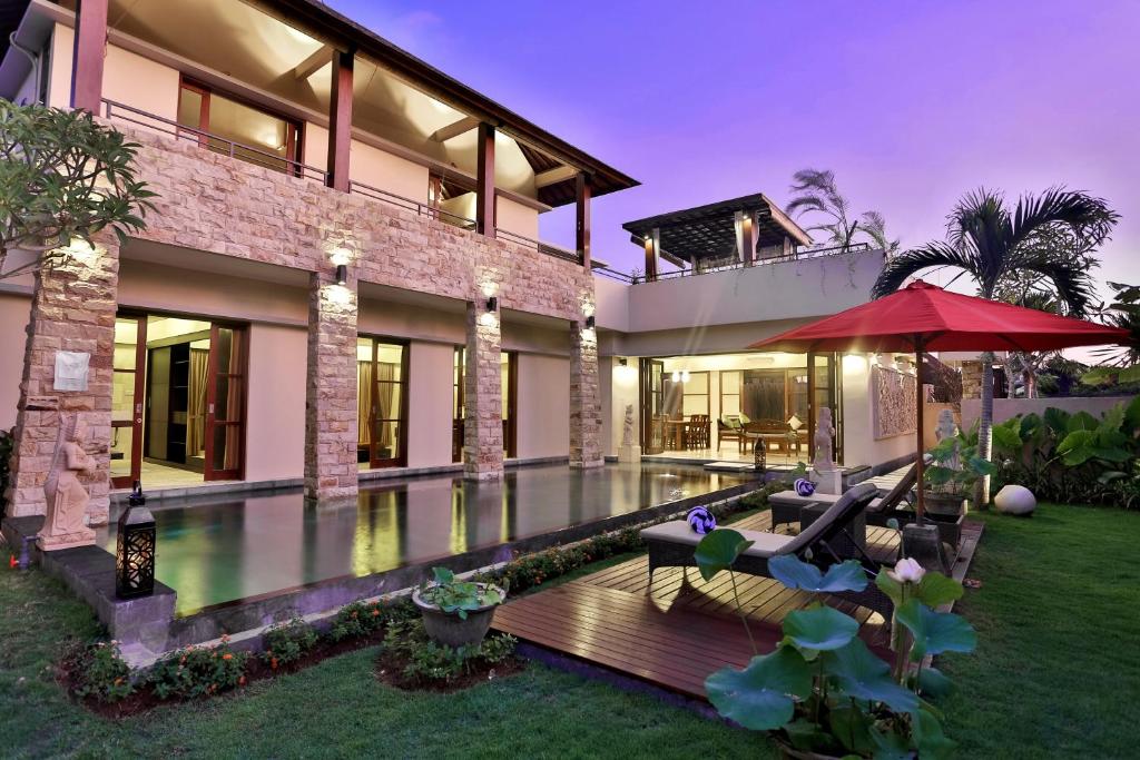 a house with a swimming pool and a red umbrella at Villa Kumuda by Nakula in Canggu