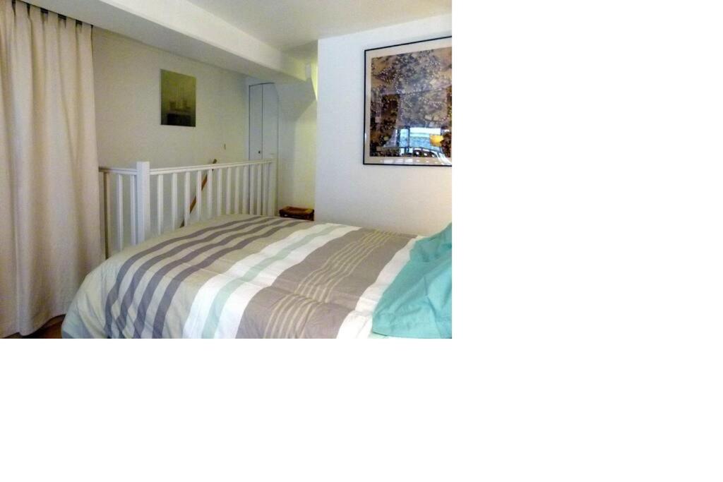 ein Schlafzimmer mit einem Bett mit einer gestreiften Decke in der Unterkunft Studio Fabert in Paris