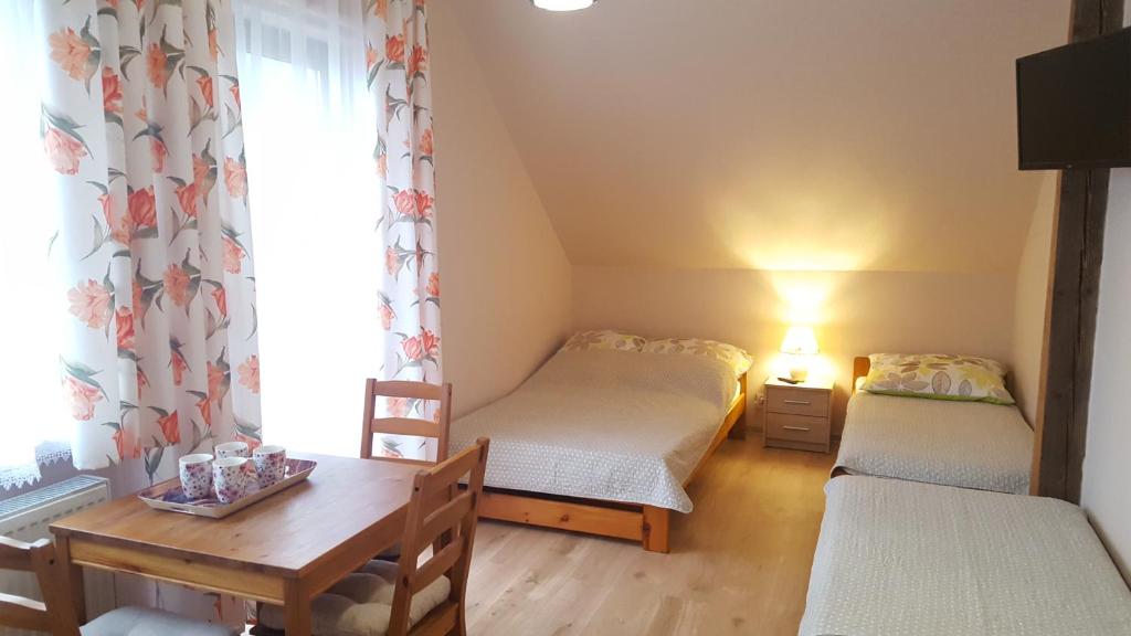 Habitación pequeña con 2 camas y mesa. en Willa Monika Zieleniec en Duszniki Zdrój