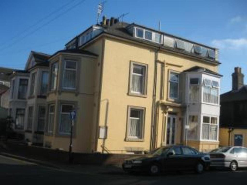 a yellow house with a car parked in front of it at 2 berth first floor flat Apsley 4 in Great Yarmouth