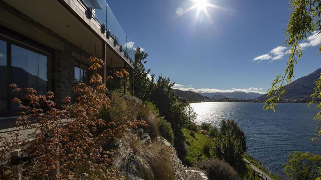 a building with a view of a lake and the sun at Kohanga Luxury Lakeside Villa by Amazing Accom in Queenstown