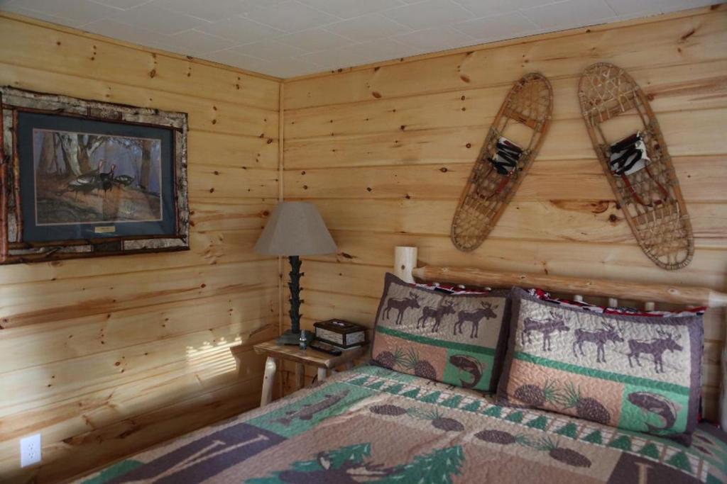a bedroom with a bed in a log cabin at Rowe's Adirondack Cabins of Schroon Lake in Schroon Lake