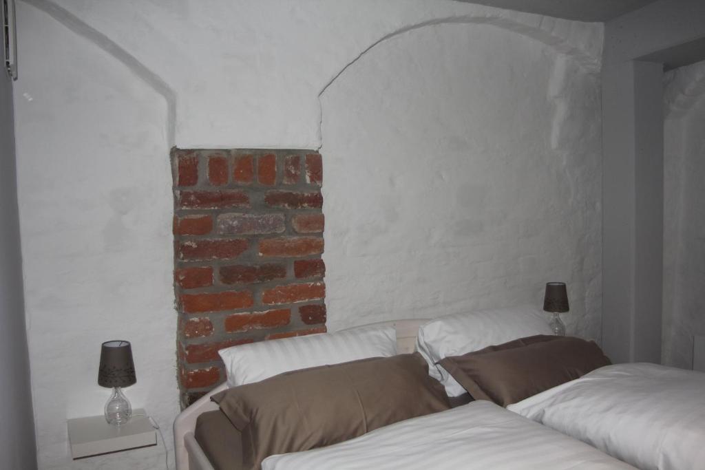 Cette chambre comprend 2 lits blancs et un mur en briques. dans l'établissement Ferienwohnung Mönch49, à Stralsund