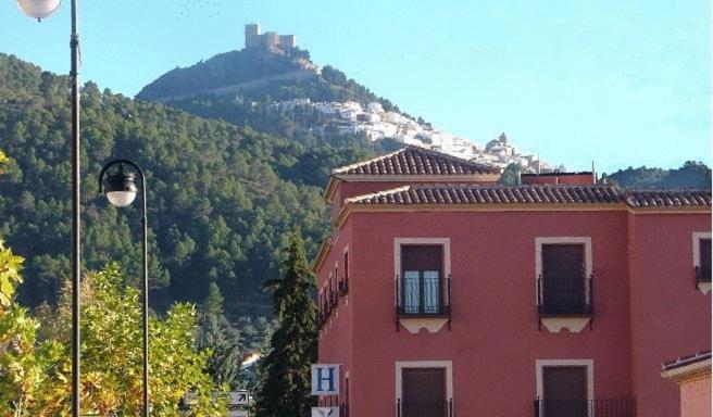 a red building in front of a mountain at Hostal Rural La Montería in Orcera