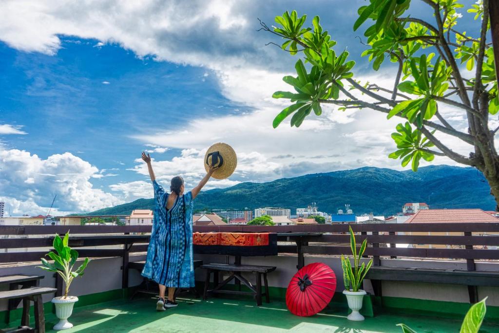 a woman standing on a balcony with her hands in the air at Ban Kong Rao Guesthouse in Chiang Mai