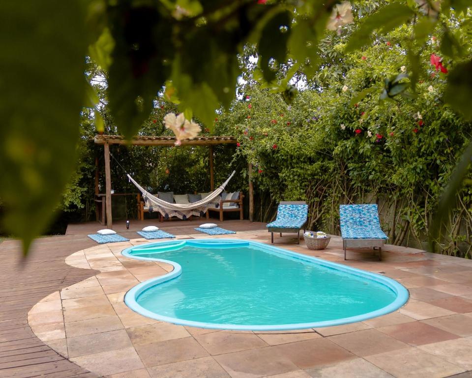 a swimming pool with two chairs and a hammock at Maras Flats in Trancoso