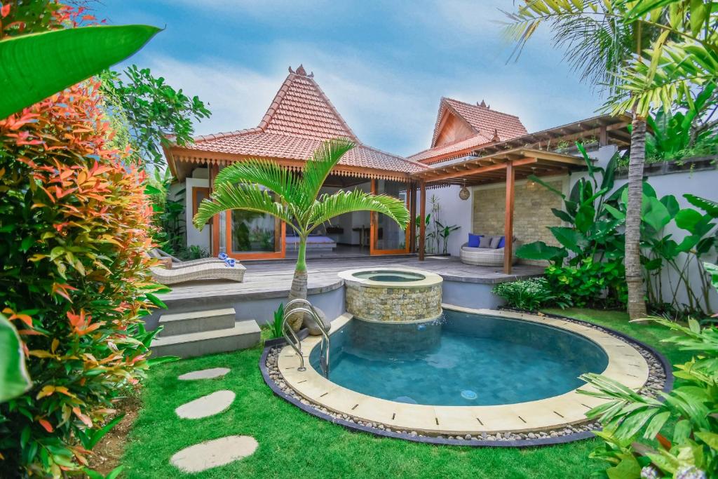 a garden with a pool in front of a house at Molokai Suites in Uluwatu