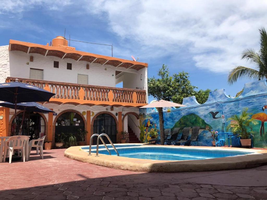 una casa con piscina frente a un edificio en Bungalows Flamingos, en Rincón de Guayabitos