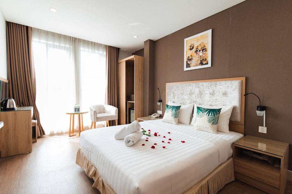 ein Schlafzimmer mit einem großen weißen Bett mit Blumen darauf in der Unterkunft My Villa Hotel - Airport in Ho-Chi-Minh-Stadt