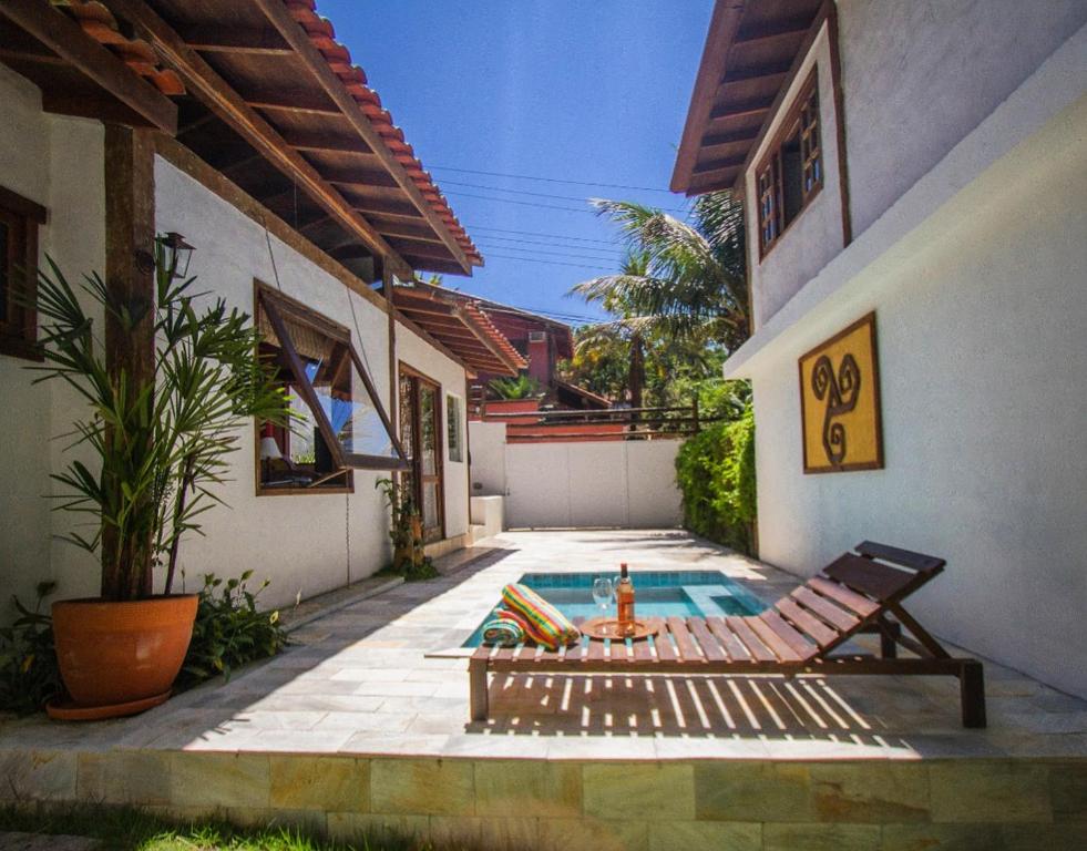 a swimming pool with a bench next to a house at Zeisa House in Maresias