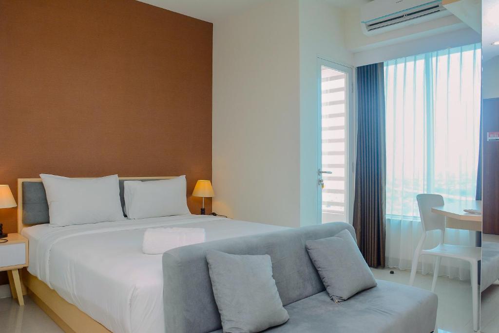 a bedroom with a large bed and a couch at Grand Kamala Lagoon Studio Apartment with Modern Interior By Travelio in Pekayon Satu