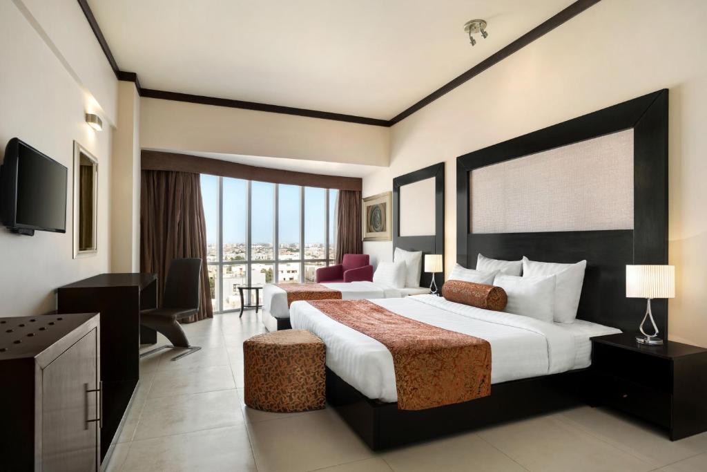 a hotel room with two beds and a television at Ramada by Wyndham Karachi Creek in Karachi