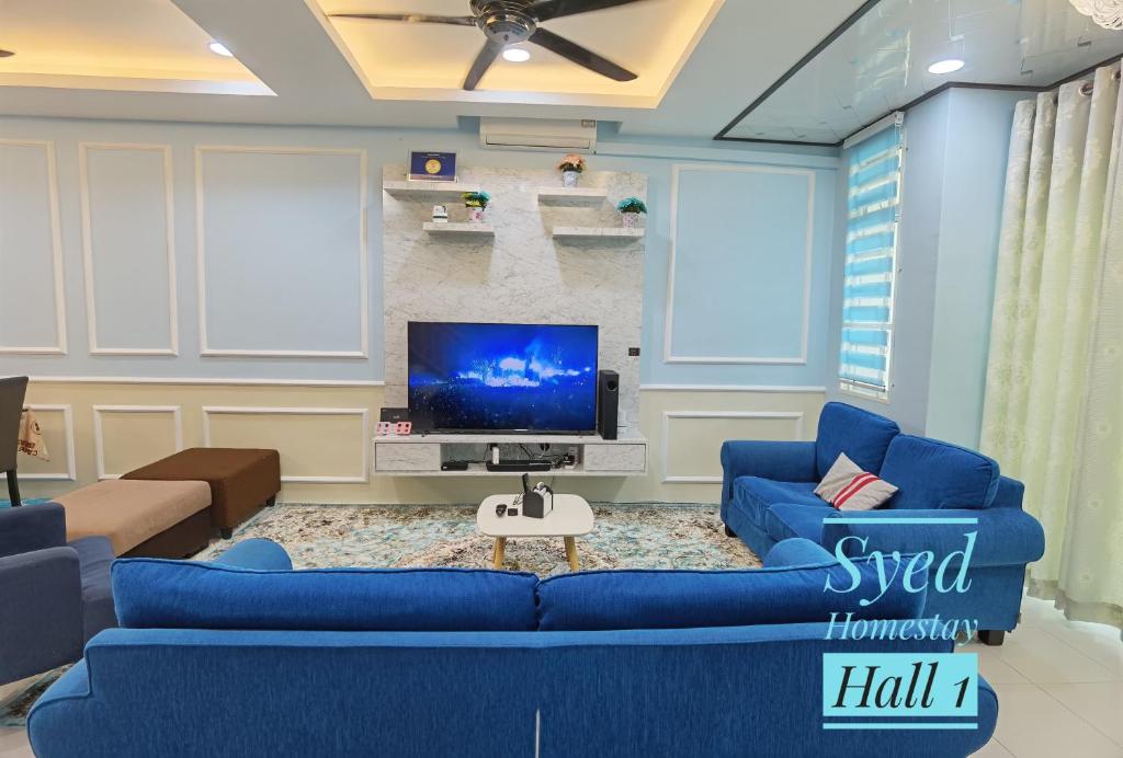 a living room with blue couches and a tv at Syed Homestay Arau in Arau