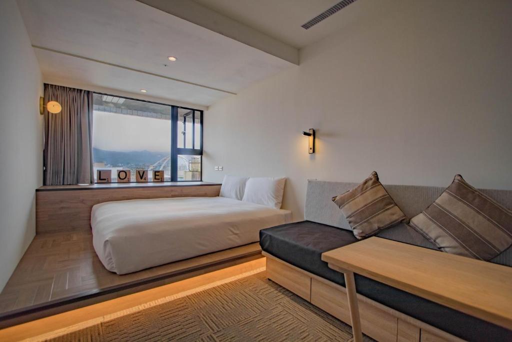 um quarto com uma cama, um sofá e uma janela em NK Hostel em Taipei