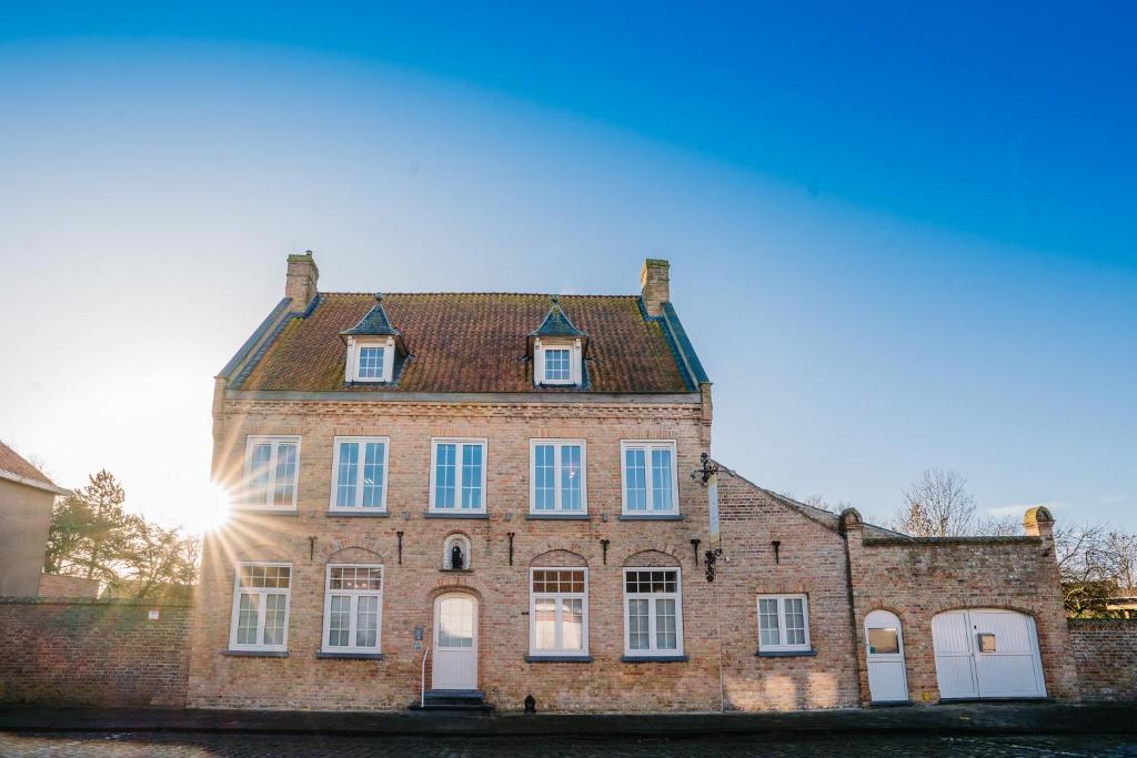 un vieux bâtiment en briques avec le soleil en arrière-plan dans l'établissement Maison de Juelle, à Middelkerke