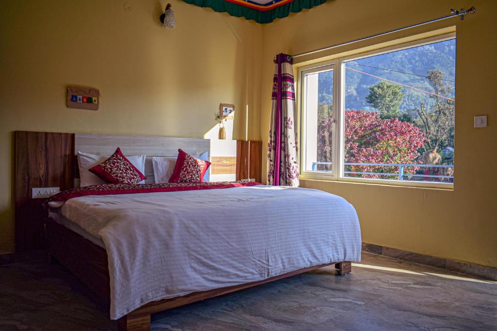 sypialnia z dużym łóżkiem i oknem w obiekcie Sakura Guest House w mieście Dharamsala