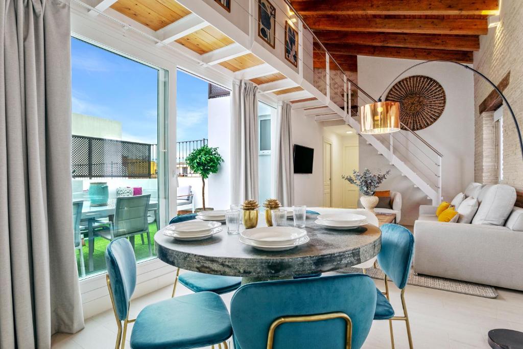 een eetkamer met een tafel en blauwe stoelen bij Genteel Home Feria in Sevilla