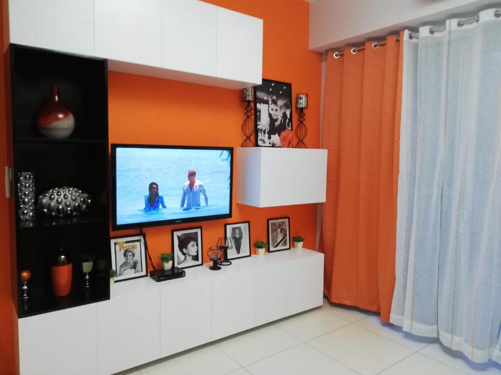 a living room with a flat screen tv on an orange wall at Lagoon view Family Suite in Pico De Loro Cove, Nasugbu in Nasugbu
