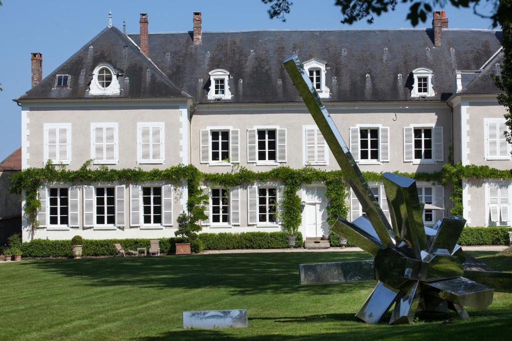 una grande casa bianca con una scultura di fronte di Chateau De La Resle - Design Hotels a Montigny-la-Resle