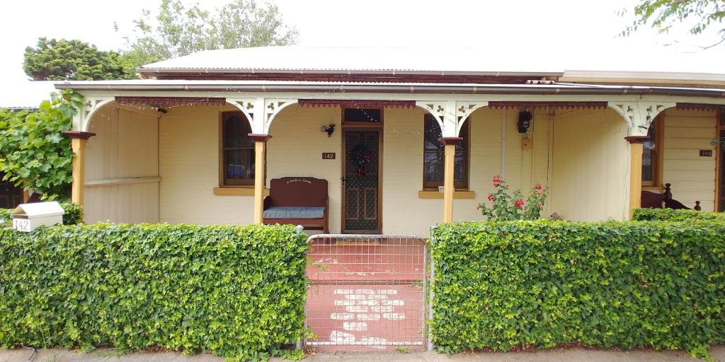 a small house with a porch and bushes at Historic cottage 200m from shops and cafes Wifi Netflix included - #142 in Bathurst