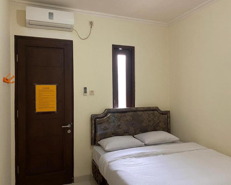 een slaapkamer met een bed en een deur met een raam bij Jatiwinangun Homestay near GOR Satria Purwoketo Mitra RedDoorz in Purwokerto