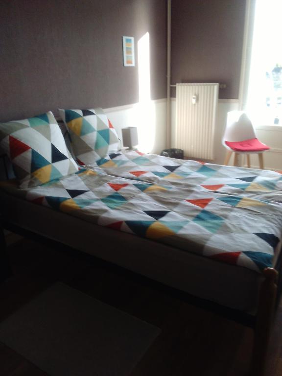 - un lit avec une couette colorée dans l'établissement Les Couesnons, à Pontorson