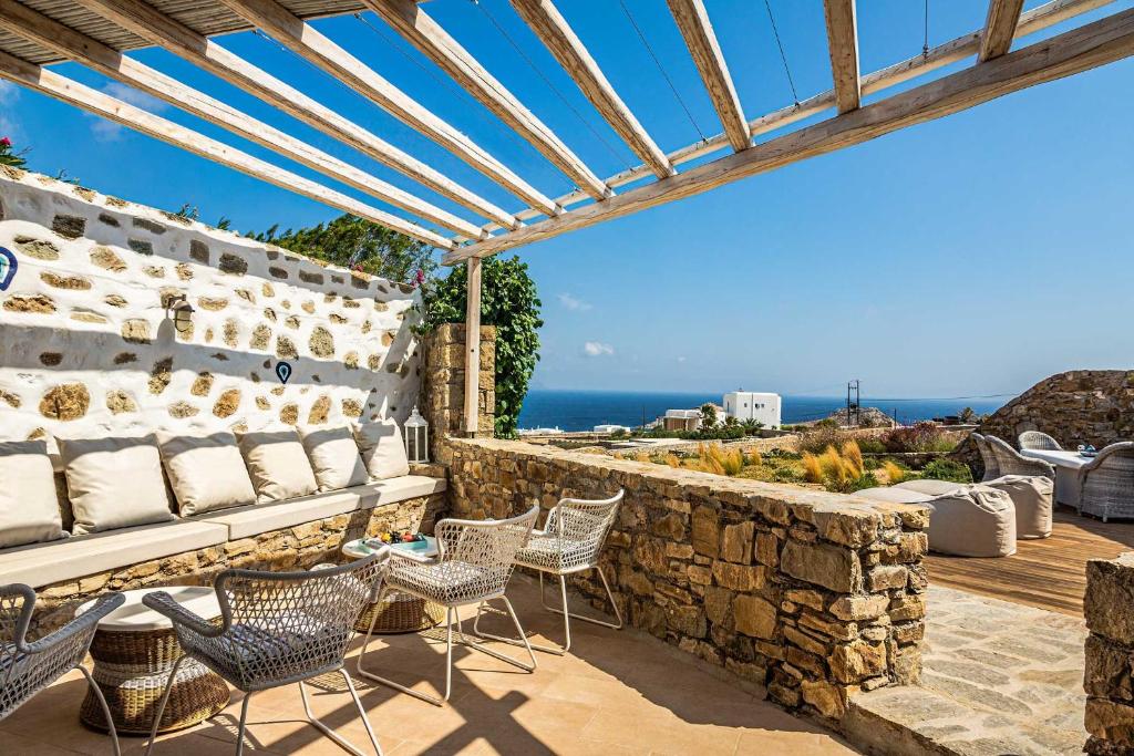 eine Terrasse mit Stühlen und Meerblick in der Unterkunft Villa Anemoni by Mykonian Kazarte in Kalafatis