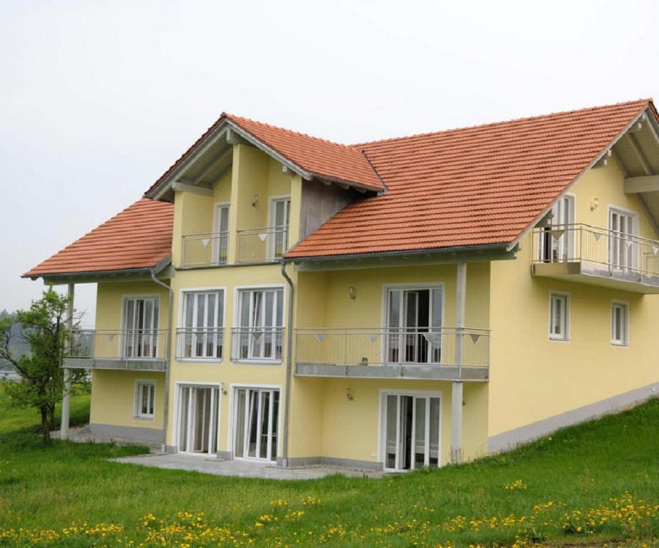 ein gelbes Haus mit rotem Dach in der Unterkunft Deinerhof in Hauzenberg