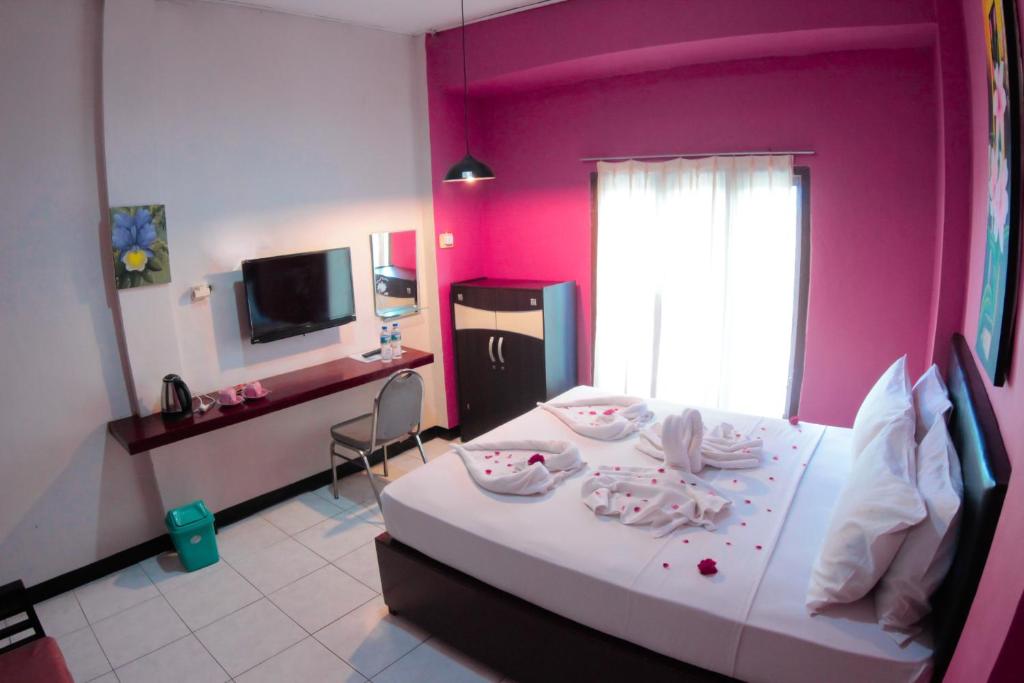 een slaapkamer met roze muren en een bed met een tafel bij Hotel FX72 Ruteng in Ruteng