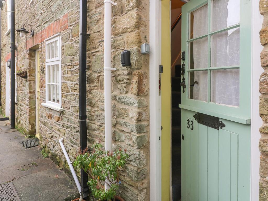 a stone house with a green door and a window at 33 Island Street in Salcombe