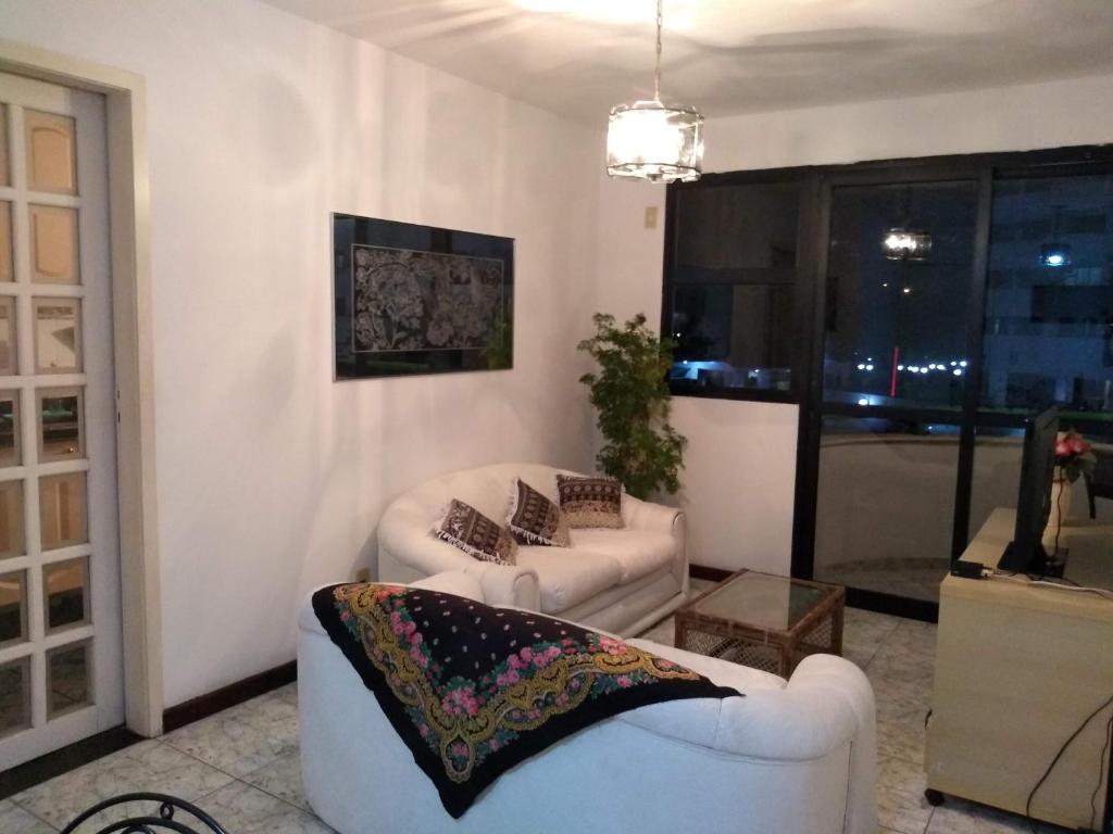 Green Bali Apartment في ريو دي جانيرو: غرفة معيشة بها كنبتين بيضاء ونافذة