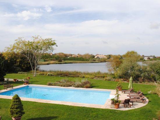 una piscina en un patio con un lago en Villa Noyaan - Luxury with pool en Southampton