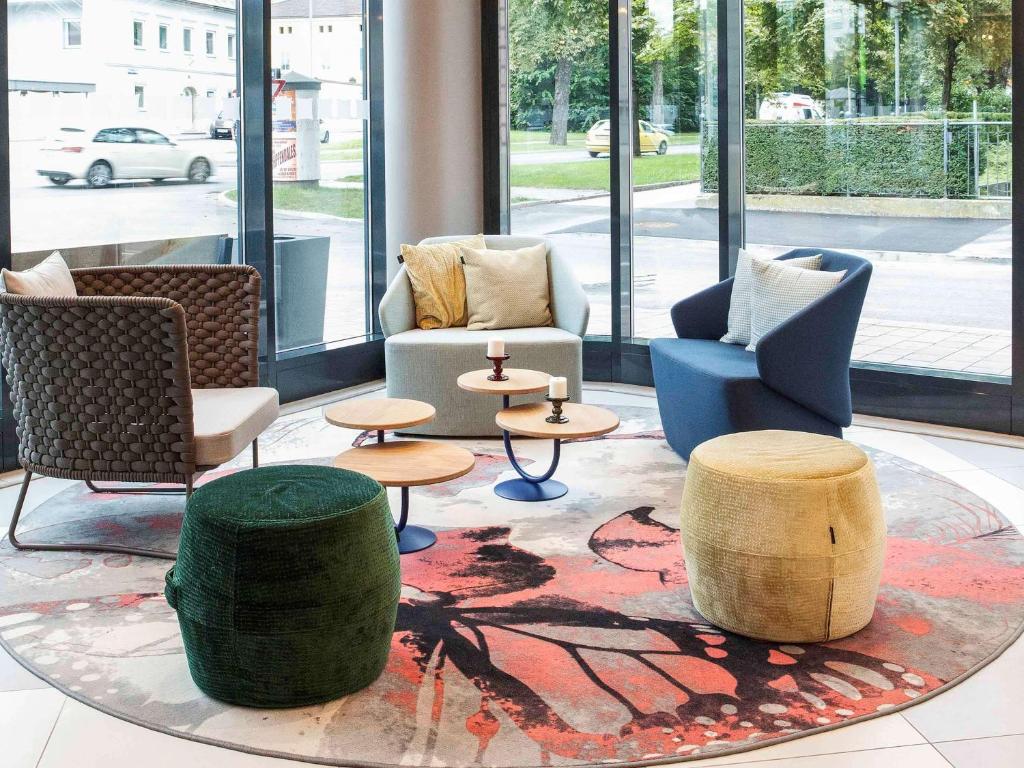 eine Lobby mit Stühlen, Tischen und Fenstern in der Unterkunft ibis Styles Klagenfurt am Woerthersee in Klagenfurt am Wörthersee