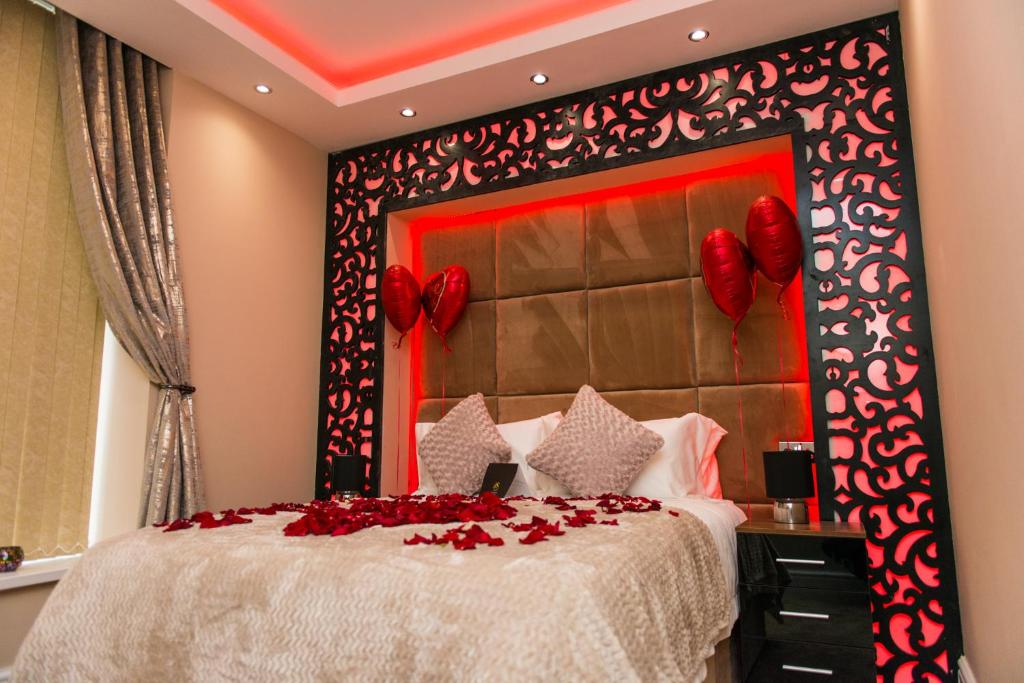 a bedroom with a large bed with red flowers on it at Aphrodite Suites Huddersfield in Huddersfield