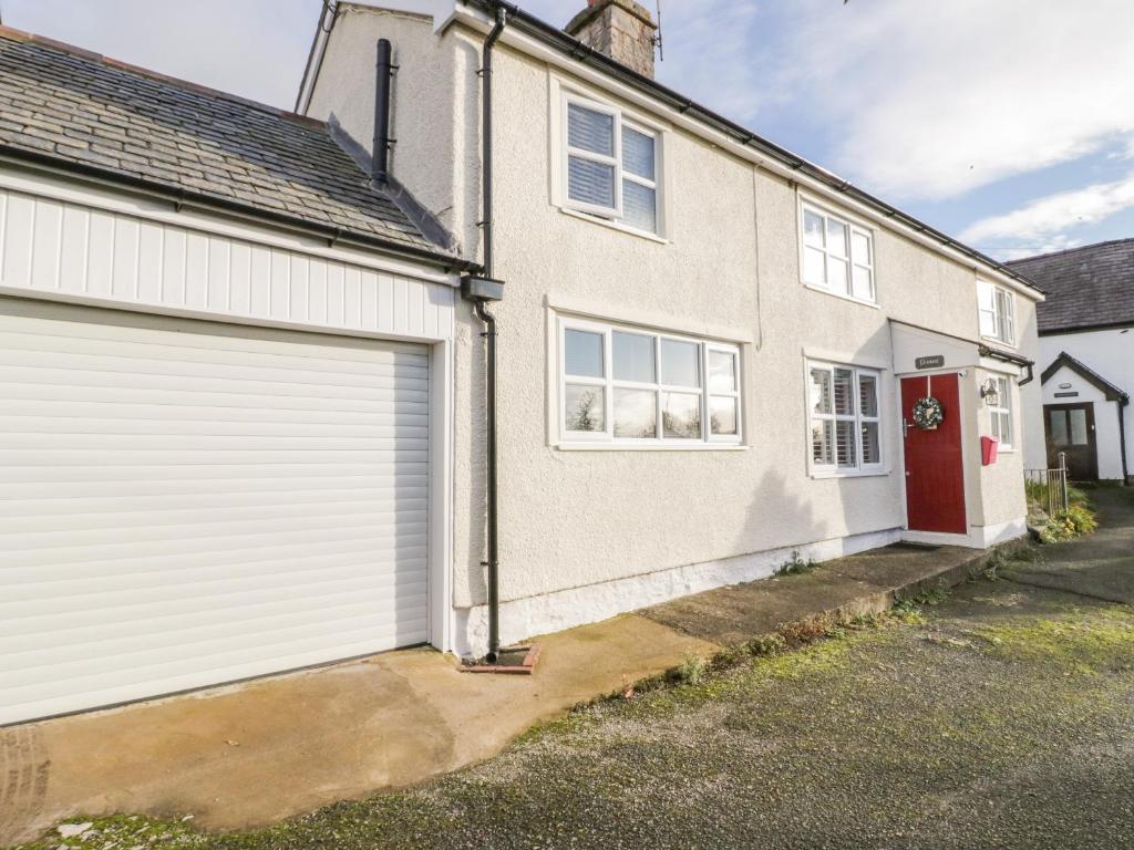 a white house with a garage and a red door at Pennant in Denbigh