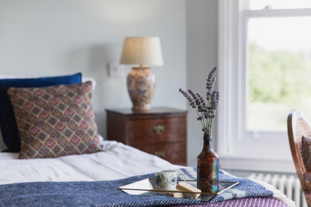 a bed with a table with a plate and a vase on it at Bridstow Guest House in Ross on Wye