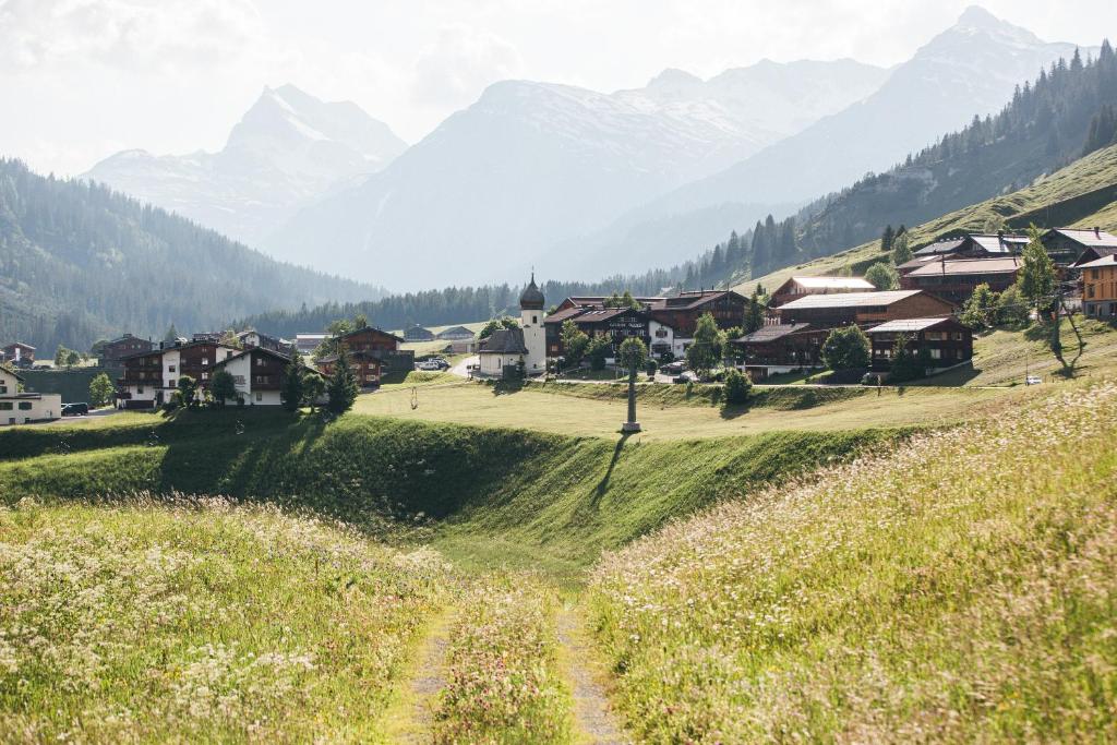 a village on a hill with mountains in the background at Walch's Rote Wand Gourmethotel in Lech am Arlberg
