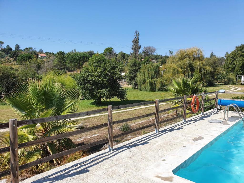 a swimming pool next to a wooden fence at Quinta Rio de Oliveira in Covas