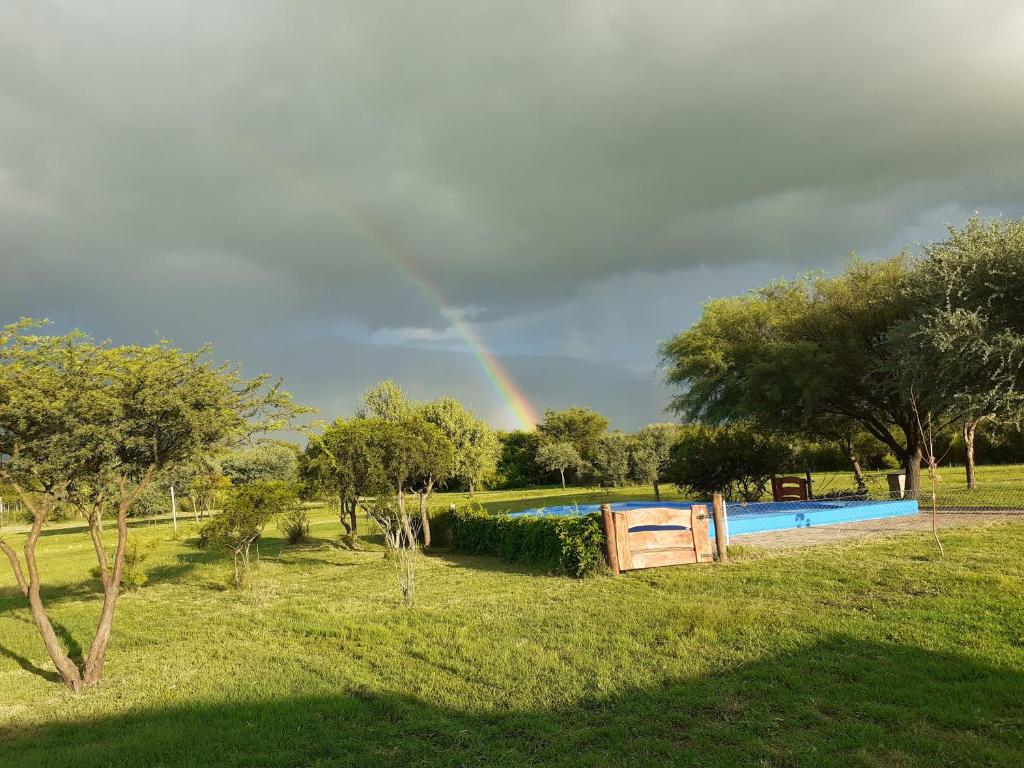 a rainbow in the sky over a swimming pool at La Nubia Cabañas in Conlara
