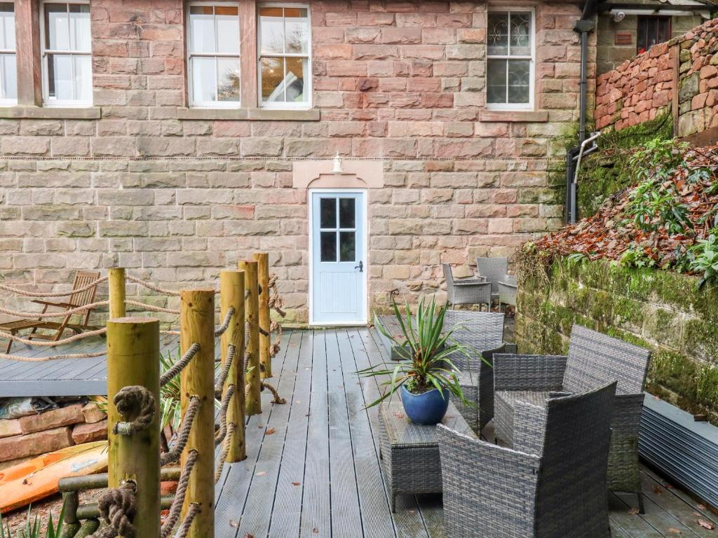 a patio with chairs and a white door and a brick building at Horton Lodge Boathouse in Leek
